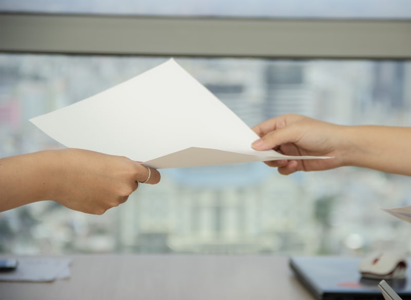 Photo of a person handing another person a paper form